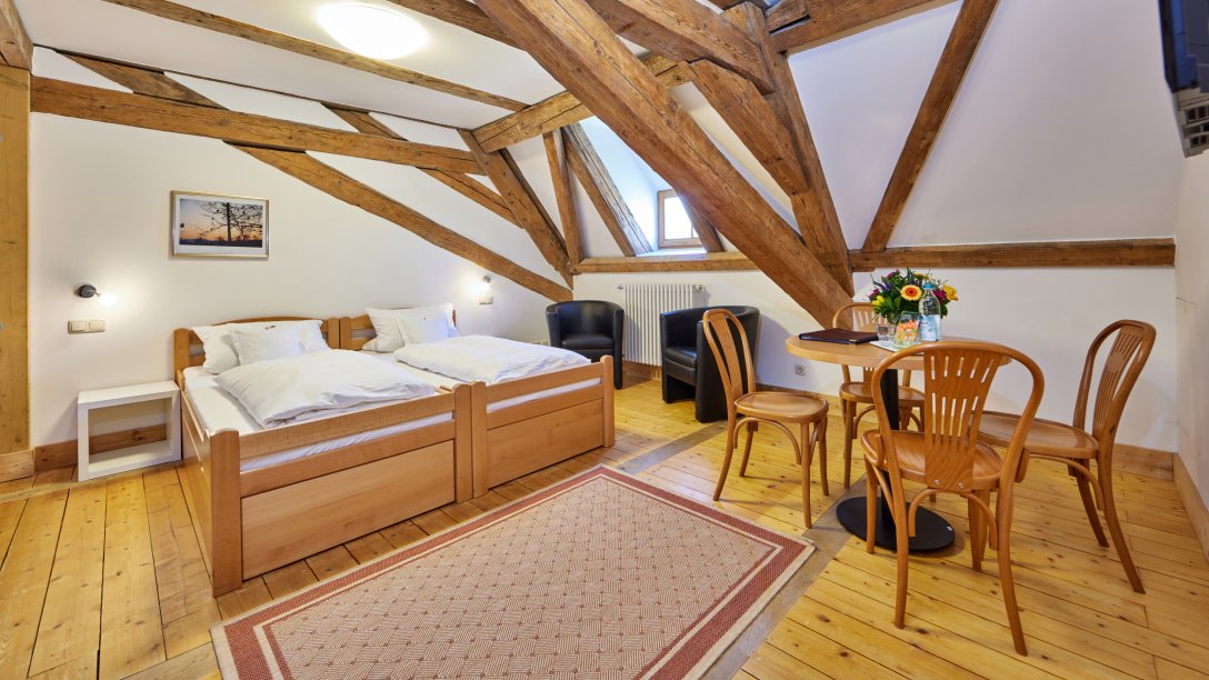 Doppelbett mit Holzgebälk und Sitzecke im Zentrum für Umwelt und Kultur