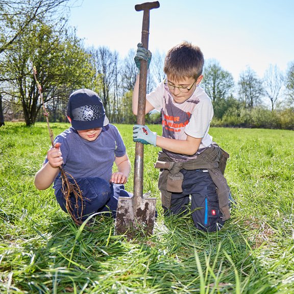 Zwei Kinder arbeiten mit Spaten auf Wiese im Gemeinschaftsgarten des ZUK 