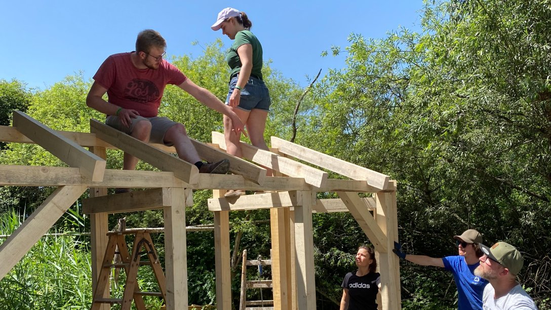 Freiwllige junge Menschen helfen beim Bau eines Holzgerüsts im Zentrum für Umwelt und Kultur